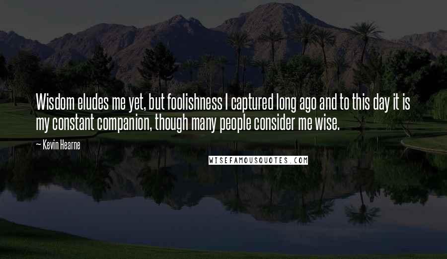 Kevin Hearne Quotes: Wisdom eludes me yet, but foolishness I captured long ago and to this day it is my constant companion, though many people consider me wise.