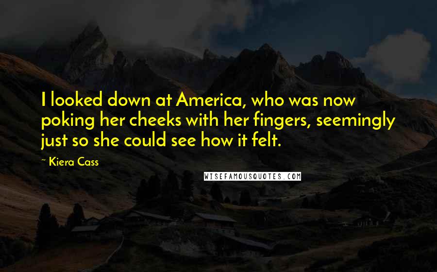 Kiera Cass Quotes: I looked down at America, who was now poking her cheeks with her fingers, seemingly just so she could see how it felt.