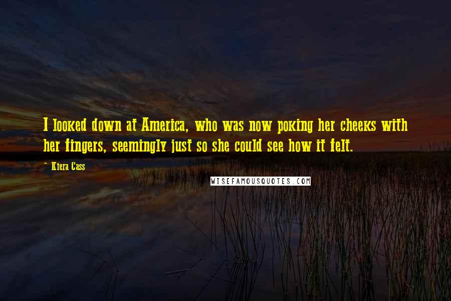 Kiera Cass Quotes: I looked down at America, who was now poking her cheeks with her fingers, seemingly just so she could see how it felt.