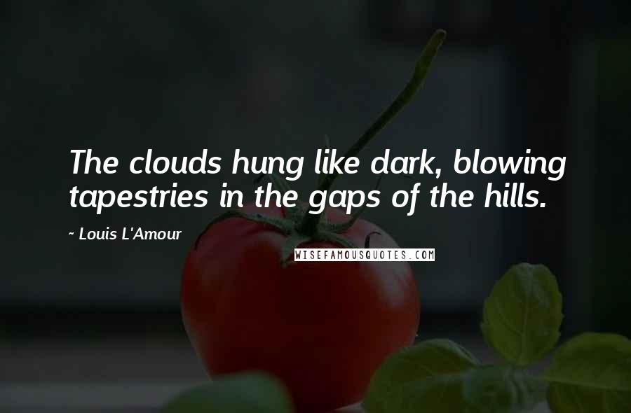 Louis L'Amour Quotes: The clouds hung like dark, blowing tapestries in the gaps of the hills.