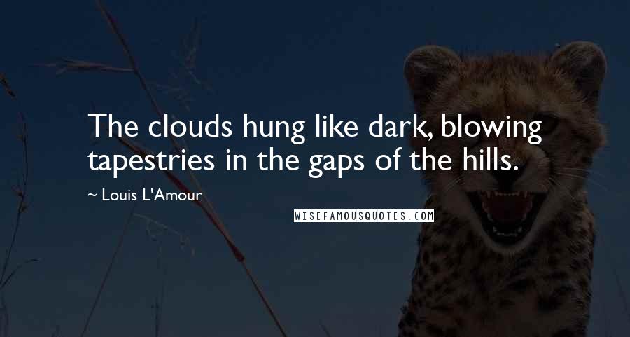 Louis L'Amour Quotes: The clouds hung like dark, blowing tapestries in the gaps of the hills.