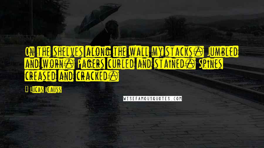 Lucas Klauss Quotes: On the shelves along the wall my stacks. Jumbled and worn. Pagers curled and stained. Spines creased and cracked.
