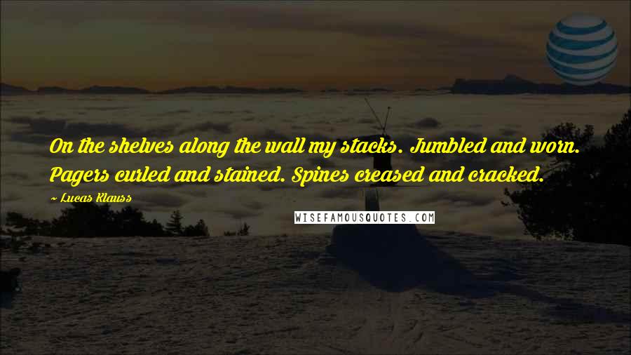 Lucas Klauss Quotes: On the shelves along the wall my stacks. Jumbled and worn. Pagers curled and stained. Spines creased and cracked.