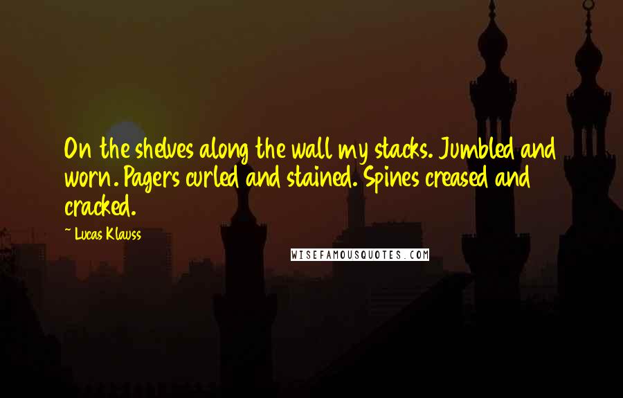 Lucas Klauss Quotes: On the shelves along the wall my stacks. Jumbled and worn. Pagers curled and stained. Spines creased and cracked.