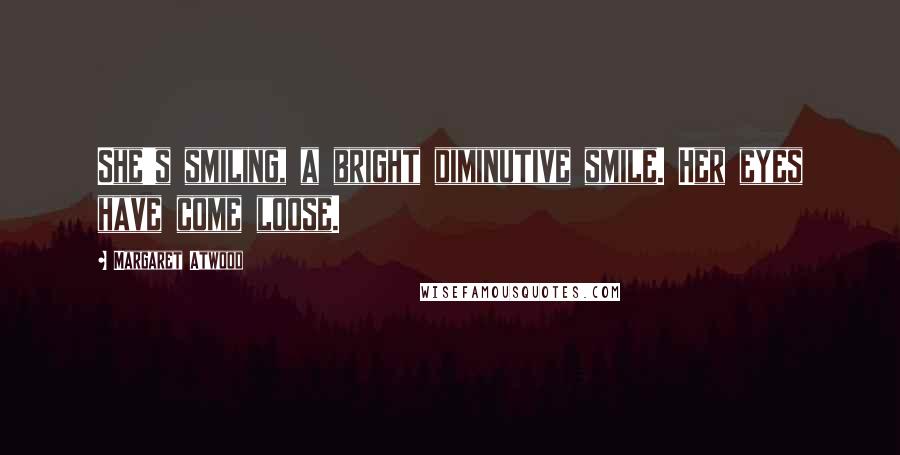 Margaret Atwood Quotes: She's smiling, a bright diminutive smile. Her eyes have come loose.