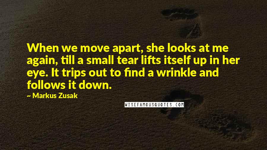 Markus Zusak Quotes: When we move apart, she looks at me again, till a small tear lifts itself up in her eye. It trips out to find a wrinkle and follows it down.