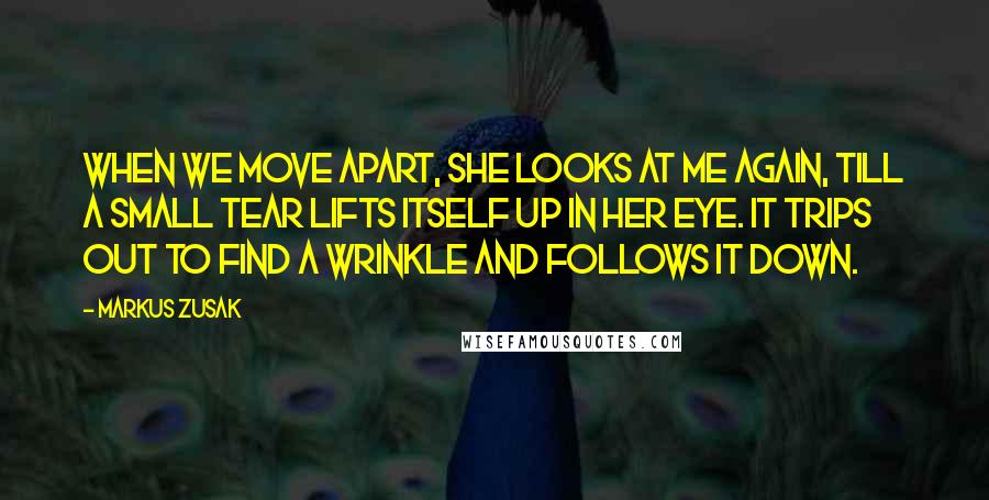 Markus Zusak Quotes: When we move apart, she looks at me again, till a small tear lifts itself up in her eye. It trips out to find a wrinkle and follows it down.