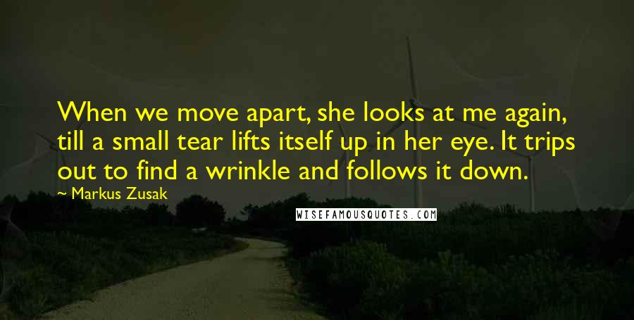 Markus Zusak Quotes: When we move apart, she looks at me again, till a small tear lifts itself up in her eye. It trips out to find a wrinkle and follows it down.