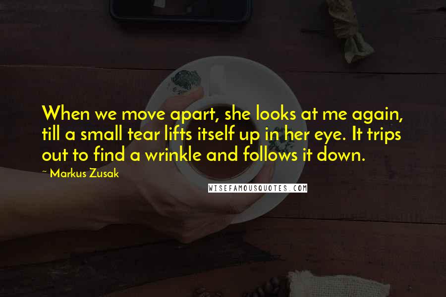 Markus Zusak Quotes: When we move apart, she looks at me again, till a small tear lifts itself up in her eye. It trips out to find a wrinkle and follows it down.