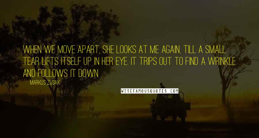 Markus Zusak Quotes: When we move apart, she looks at me again, till a small tear lifts itself up in her eye. It trips out to find a wrinkle and follows it down.