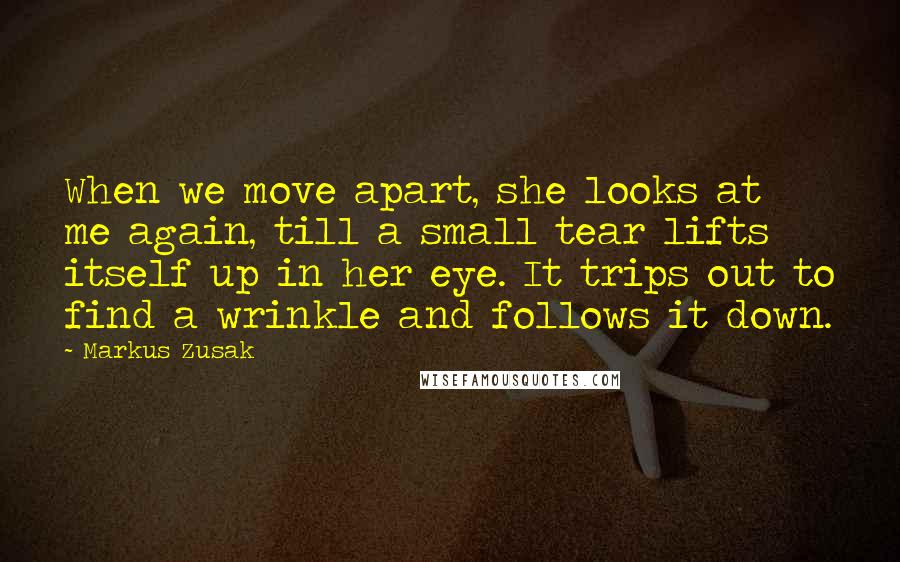 Markus Zusak Quotes: When we move apart, she looks at me again, till a small tear lifts itself up in her eye. It trips out to find a wrinkle and follows it down.