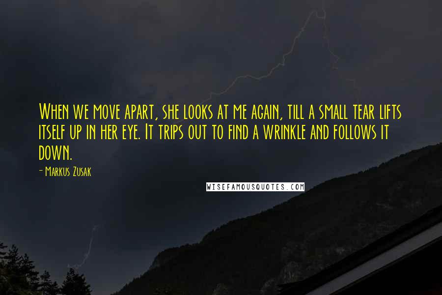 Markus Zusak Quotes: When we move apart, she looks at me again, till a small tear lifts itself up in her eye. It trips out to find a wrinkle and follows it down.