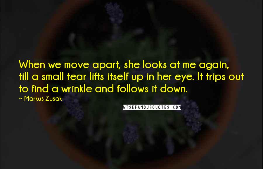 Markus Zusak Quotes: When we move apart, she looks at me again, till a small tear lifts itself up in her eye. It trips out to find a wrinkle and follows it down.
