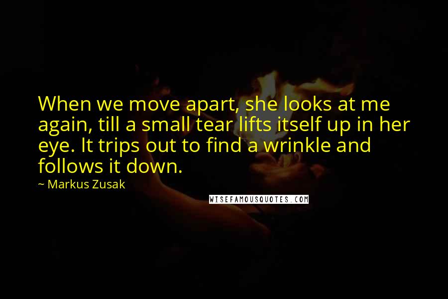 Markus Zusak Quotes: When we move apart, she looks at me again, till a small tear lifts itself up in her eye. It trips out to find a wrinkle and follows it down.