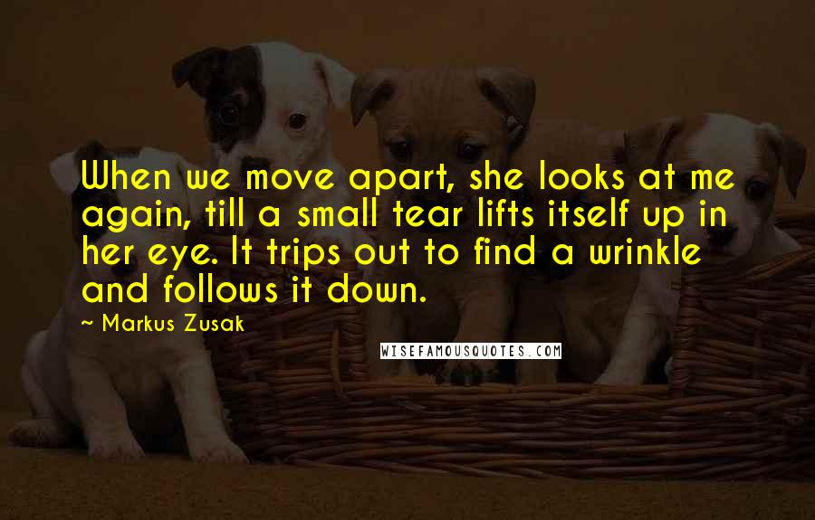 Markus Zusak Quotes: When we move apart, she looks at me again, till a small tear lifts itself up in her eye. It trips out to find a wrinkle and follows it down.