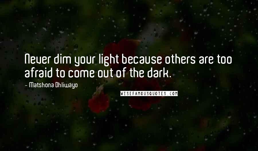 Matshona Dhliwayo Quotes: Never dim your light because others are too afraid to come out of the dark.