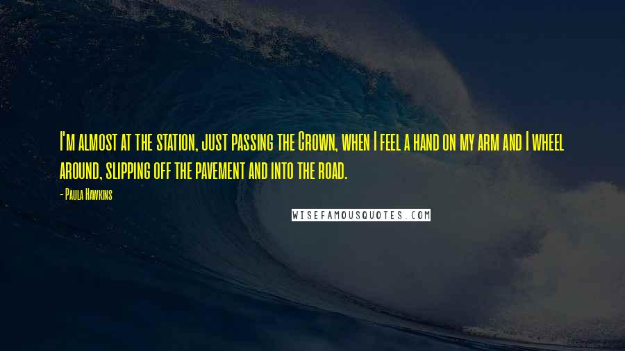 Paula Hawkins Quotes: I'm almost at the station, just passing the Crown, when I feel a hand on my arm and I wheel around, slipping off the pavement and into the road.