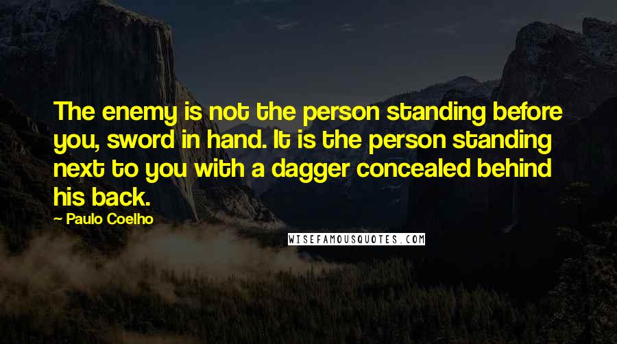 Paulo Coelho Quotes: The enemy is not the person standing before you, sword in hand. It is the person standing next to you with a dagger concealed behind his back.