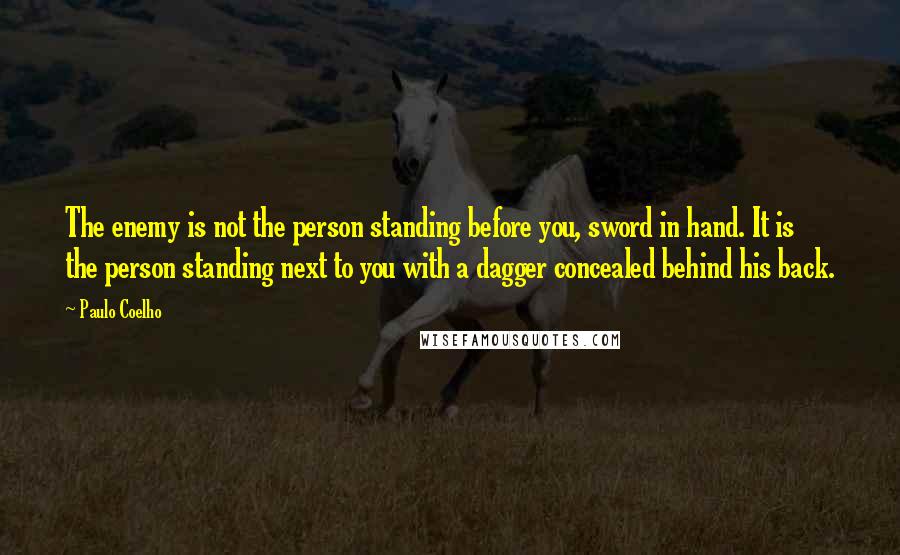 Paulo Coelho Quotes: The enemy is not the person standing before you, sword in hand. It is the person standing next to you with a dagger concealed behind his back.