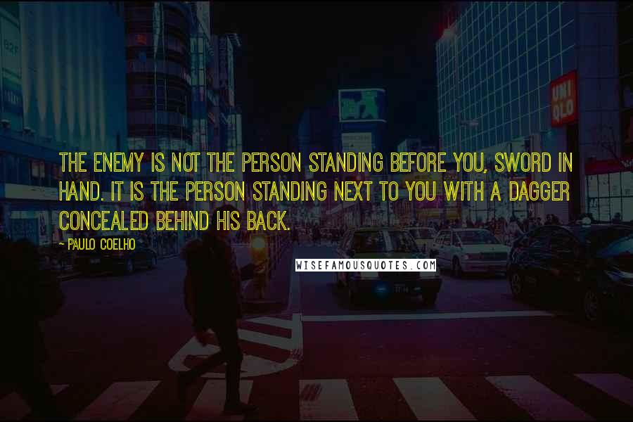 Paulo Coelho Quotes: The enemy is not the person standing before you, sword in hand. It is the person standing next to you with a dagger concealed behind his back.