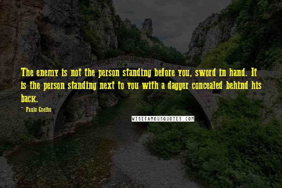 Paulo Coelho Quotes: The enemy is not the person standing before you, sword in hand. It is the person standing next to you with a dagger concealed behind his back.