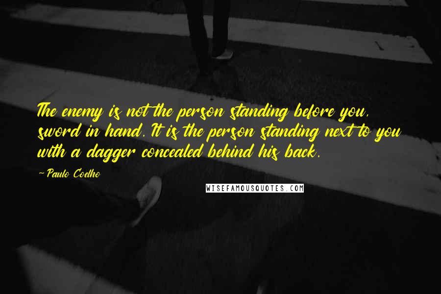 Paulo Coelho Quotes: The enemy is not the person standing before you, sword in hand. It is the person standing next to you with a dagger concealed behind his back.