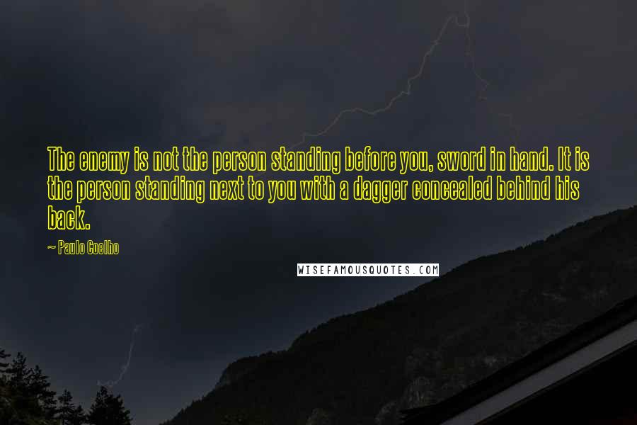 Paulo Coelho Quotes: The enemy is not the person standing before you, sword in hand. It is the person standing next to you with a dagger concealed behind his back.