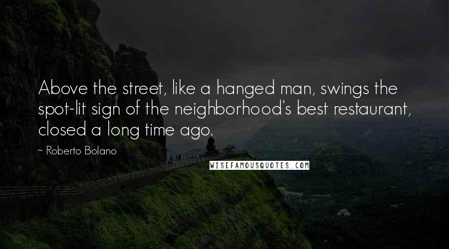 Roberto Bolano Quotes: Above the street, like a hanged man, swings the spot-lit sign of the neighborhood's best restaurant, closed a long time ago.