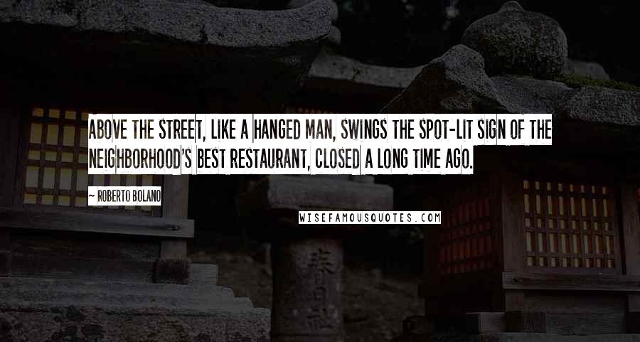 Roberto Bolano Quotes: Above the street, like a hanged man, swings the spot-lit sign of the neighborhood's best restaurant, closed a long time ago.