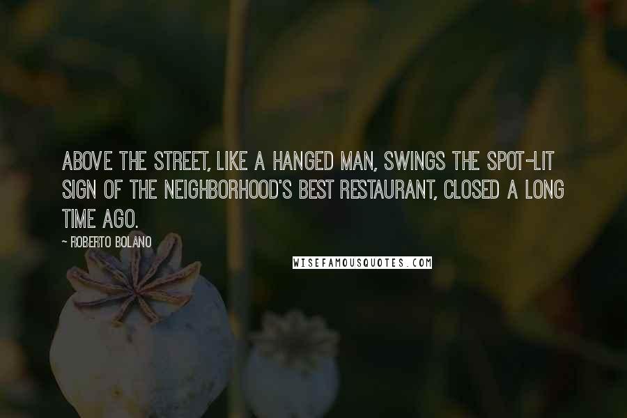 Roberto Bolano Quotes: Above the street, like a hanged man, swings the spot-lit sign of the neighborhood's best restaurant, closed a long time ago.