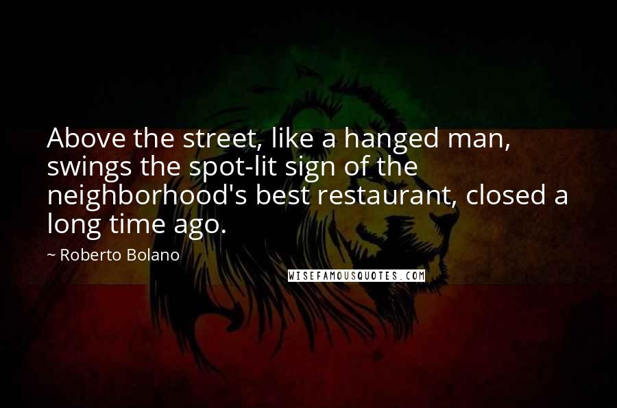 Roberto Bolano Quotes: Above the street, like a hanged man, swings the spot-lit sign of the neighborhood's best restaurant, closed a long time ago.