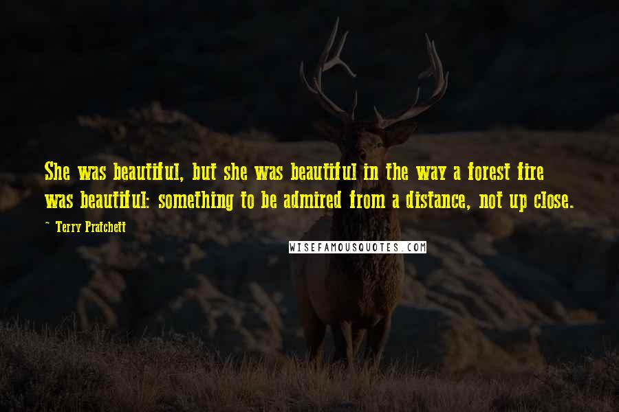 Terry Pratchett Quotes: She was beautiful, but she was beautiful in the way a forest fire was beautiful: something to be admired from a distance, not up close.