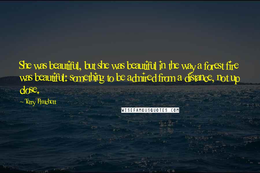 Terry Pratchett Quotes: She was beautiful, but she was beautiful in the way a forest fire was beautiful: something to be admired from a distance, not up close.