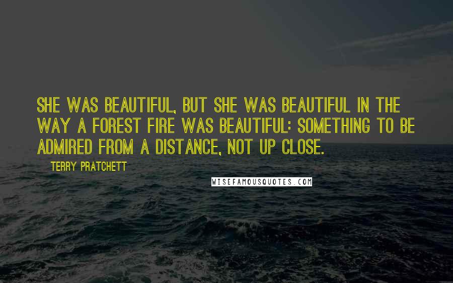 Terry Pratchett Quotes: She was beautiful, but she was beautiful in the way a forest fire was beautiful: something to be admired from a distance, not up close.