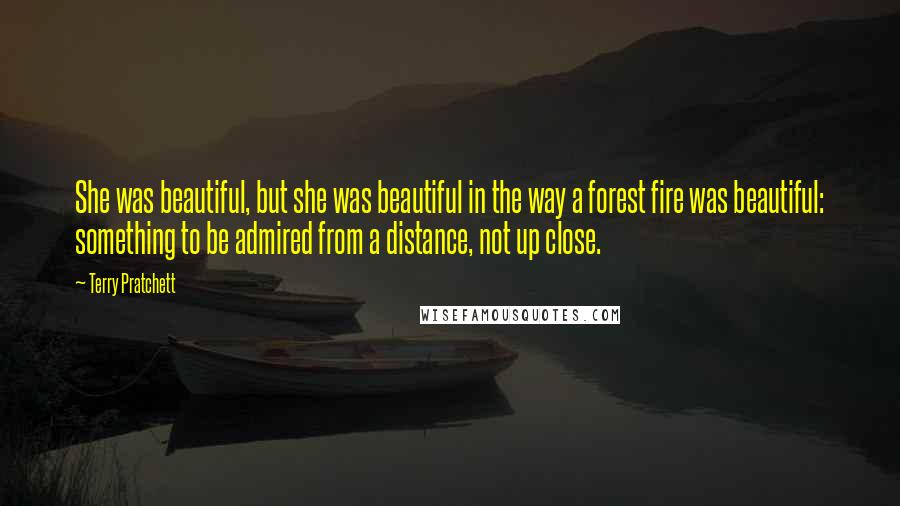 Terry Pratchett Quotes: She was beautiful, but she was beautiful in the way a forest fire was beautiful: something to be admired from a distance, not up close.