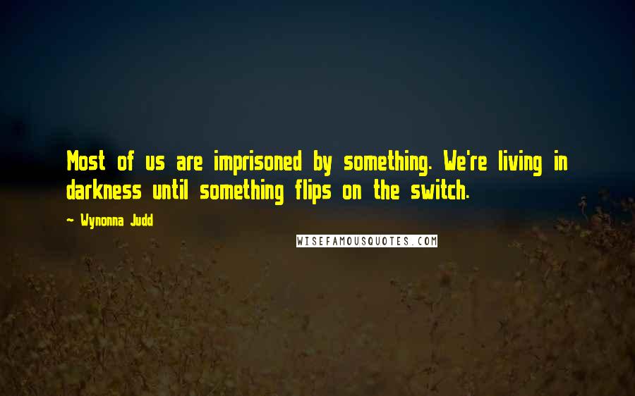 Wynonna Judd Quotes: Most of us are imprisoned by something. We're living in darkness until something flips on the switch.