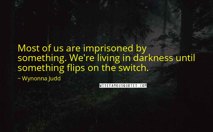 Wynonna Judd Quotes: Most of us are imprisoned by something. We're living in darkness until something flips on the switch.